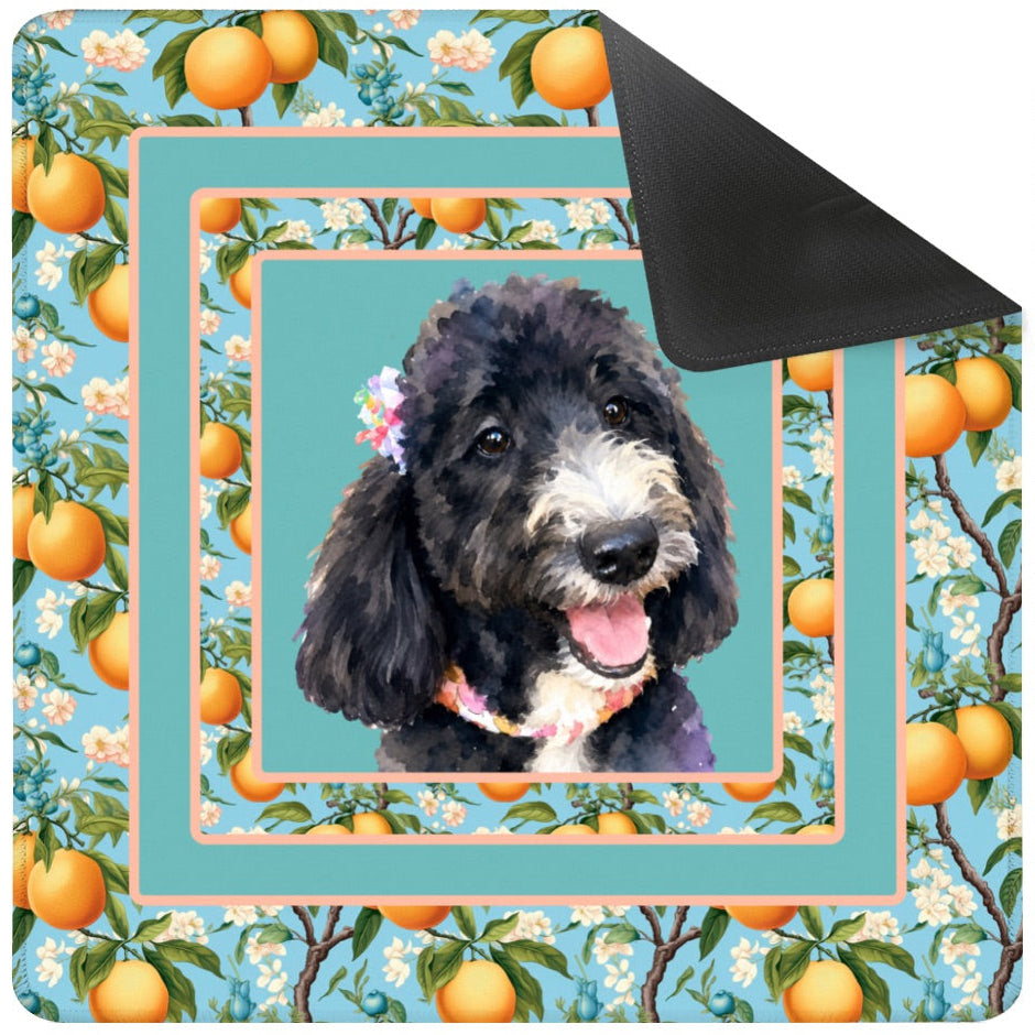 Dog blanket with a floral and orange design, featuring a dog's face in the center, with a black carrying bag on the side.