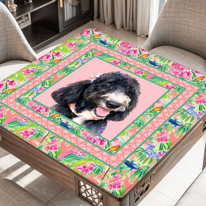Table with floral tablecloth featuring a dog, surrounded by playing cards and dominoes.