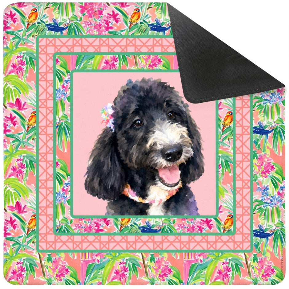 Floral-patterned dog blanket with a black dog on a pink background, accompanied by a black carrying bag.